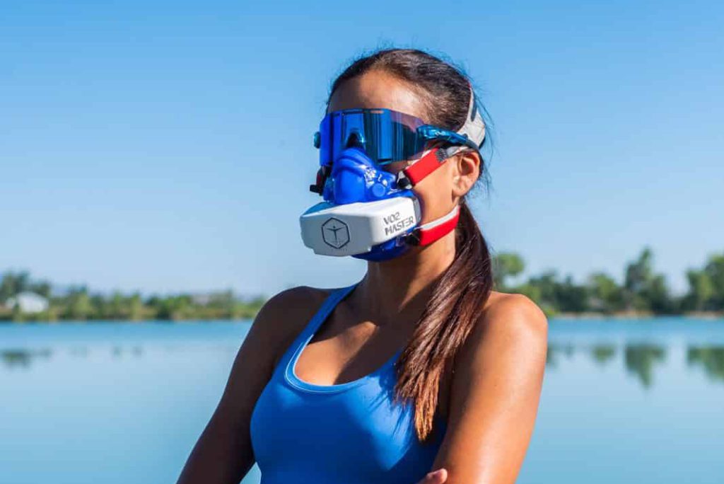 Athletic female standing by water wearing sunglasses and the VO2 Master Analyzer after swim