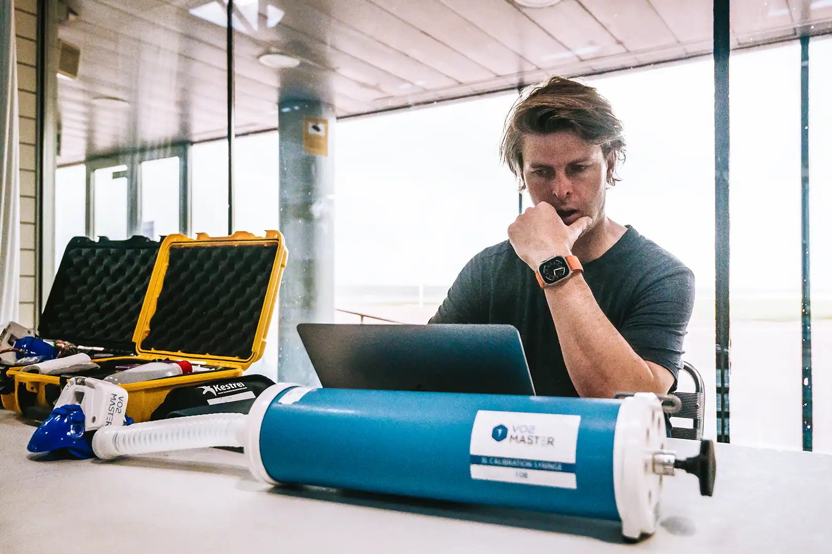 Coach Olav Aleksander Bu reviewing data beside portable metabolic testing equipment including a calibration syringe and VO2 Master analyzer kit.