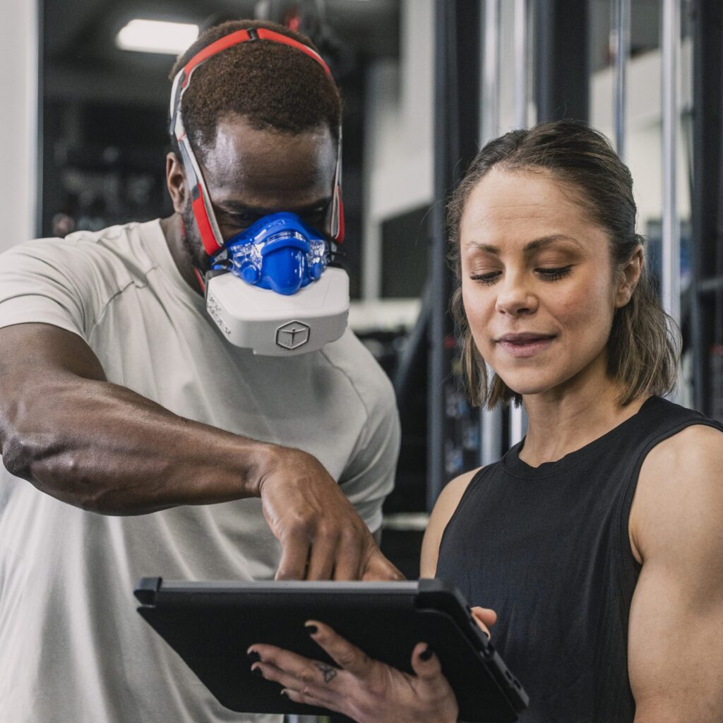 Man and woman reviewing performance analyzer results on an iPad inside an athletic facility