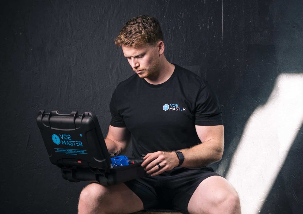 athletic male opening up the VO2 Master analyzer kit inside a dark fitness facility