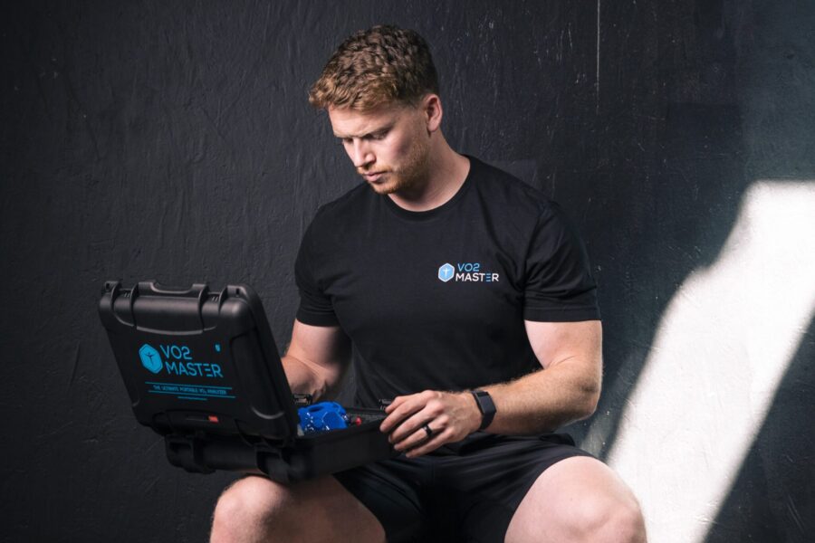 athletic male opening up the VO2 Master analyzer kit inside a dark fitness facility