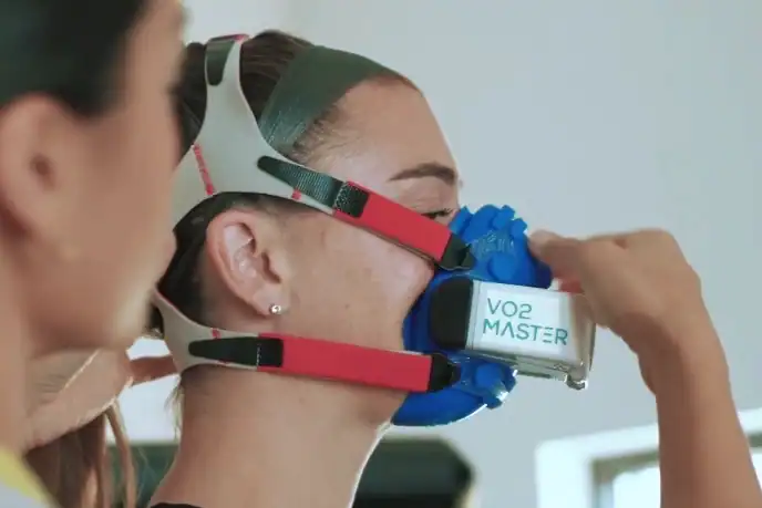 Trainer adjusts the VO2 Master Analyzer for portable metabolic assessment and heart rate zone testing under trainer supervision.