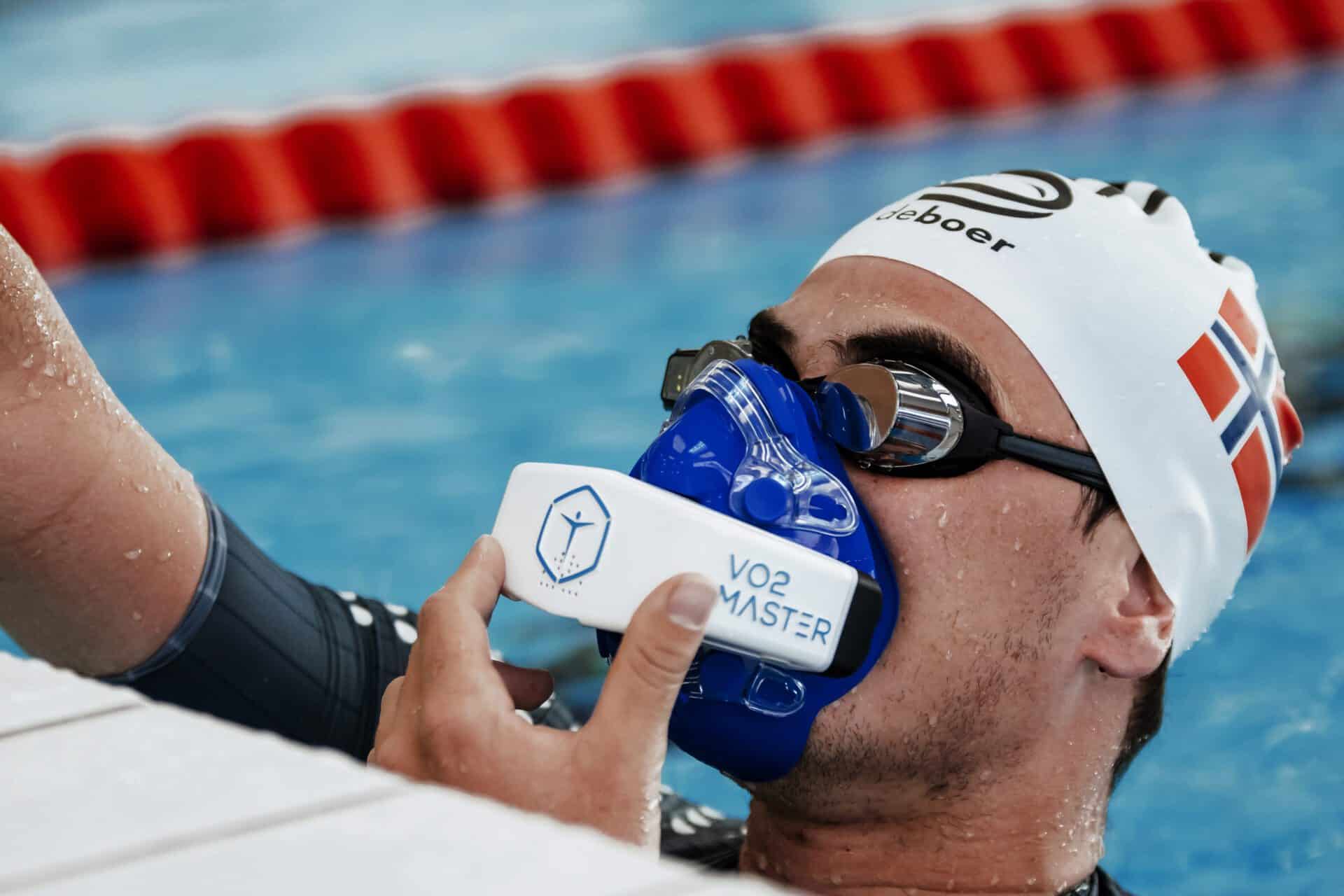 Swimmer coming up for air in a pool and breathing through the VO2 Master mask and performance analyzer
