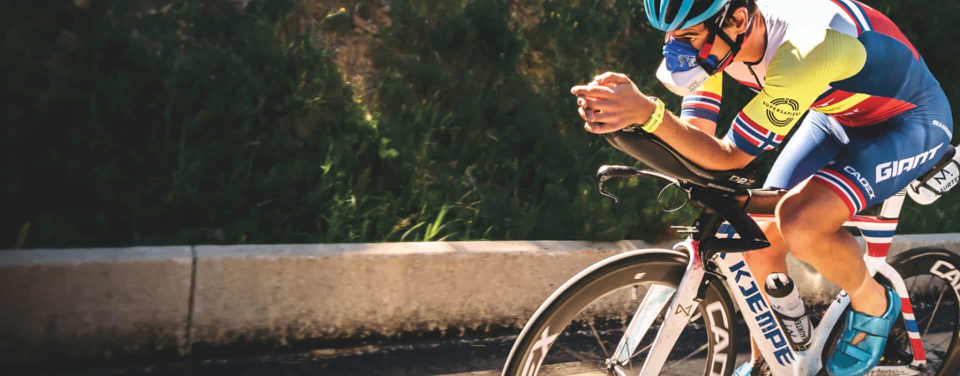 An athlete is shown biking on the road wearing the vo2 master analyzer portable device.