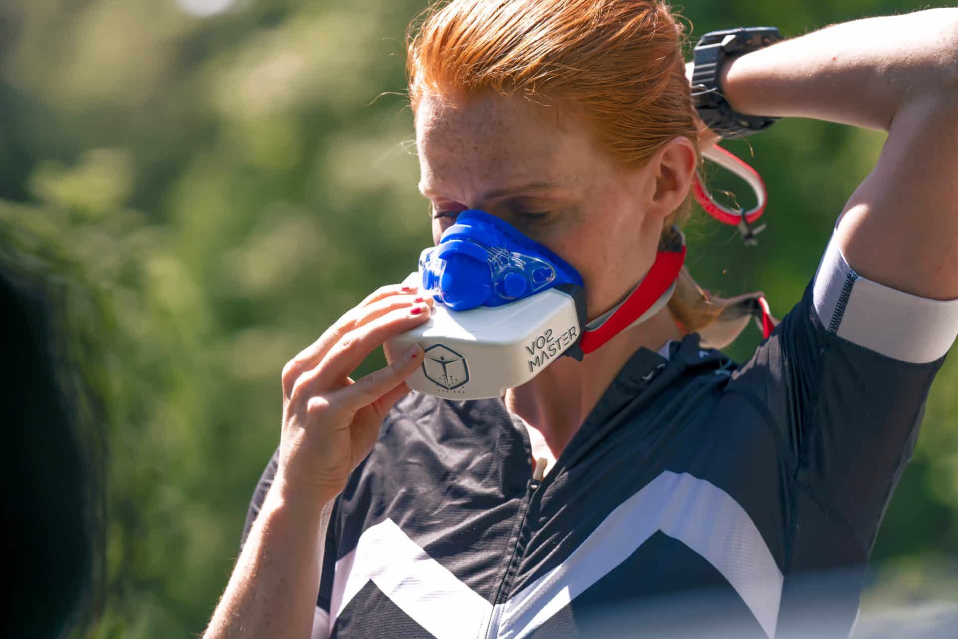 Woman strapping on the VO2 Master analyzer and blue Hans Rudolph mask outdoors