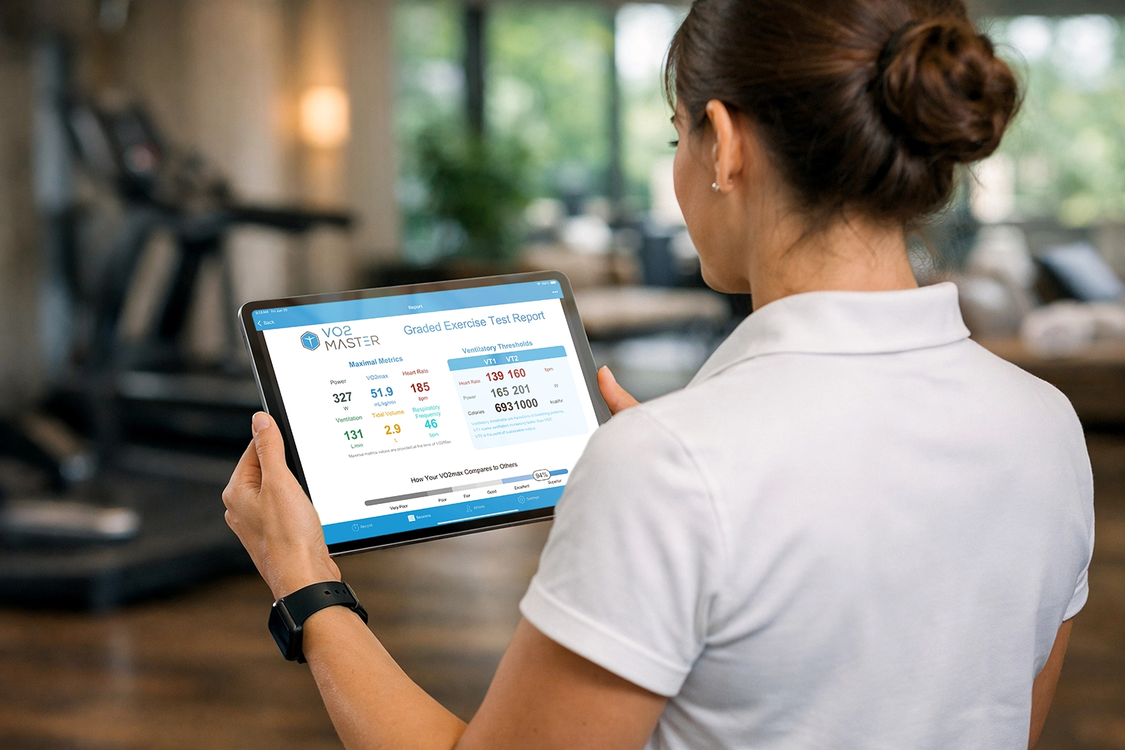 Wellness professional reviews a graded exercise test report on a tablet in a luxury fitness or hospitality setting.