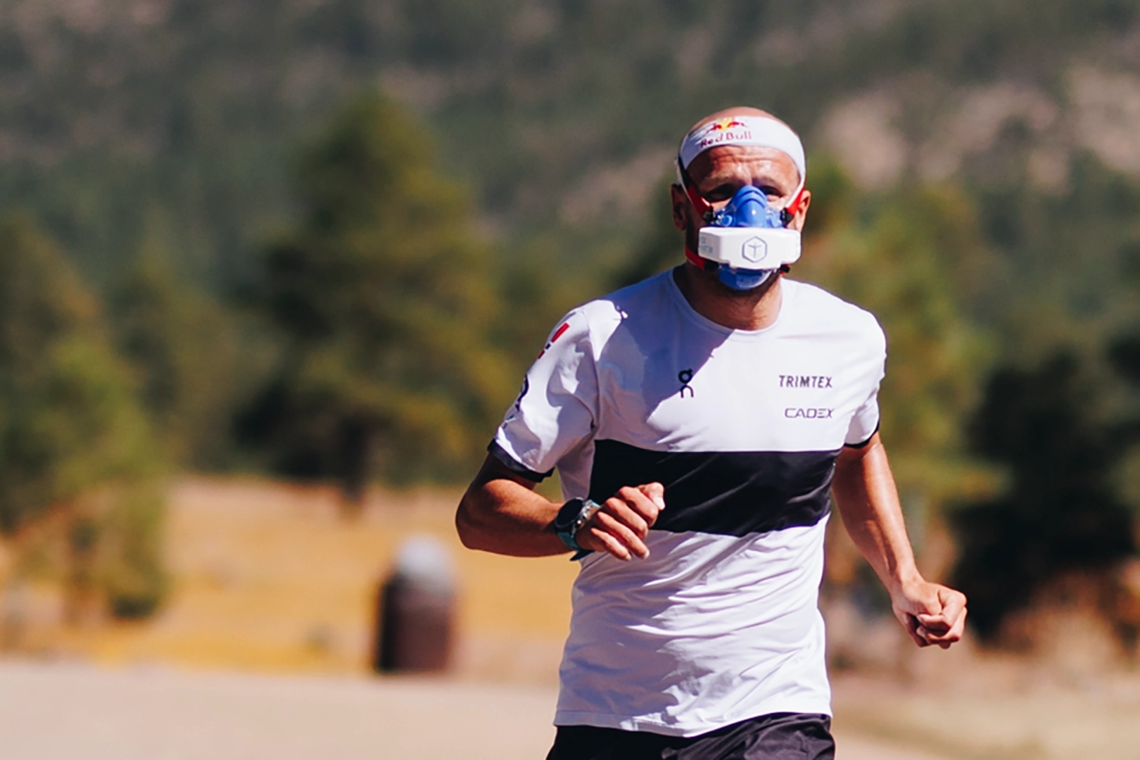 Kristian Blummenfelt wearing a portable VO2 mask during outdoor submax VO2 testing on a road with a natural background.