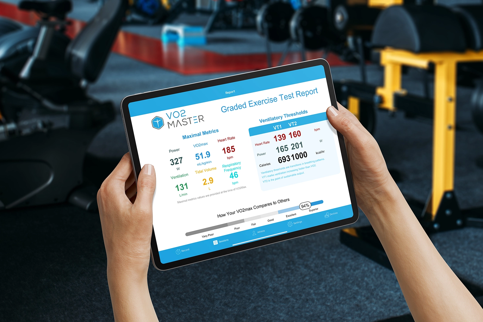 Tablet displaying a graded exercise test report with VO2 Max, heart rate, ventilation, and threshold metrics in a training facility.
