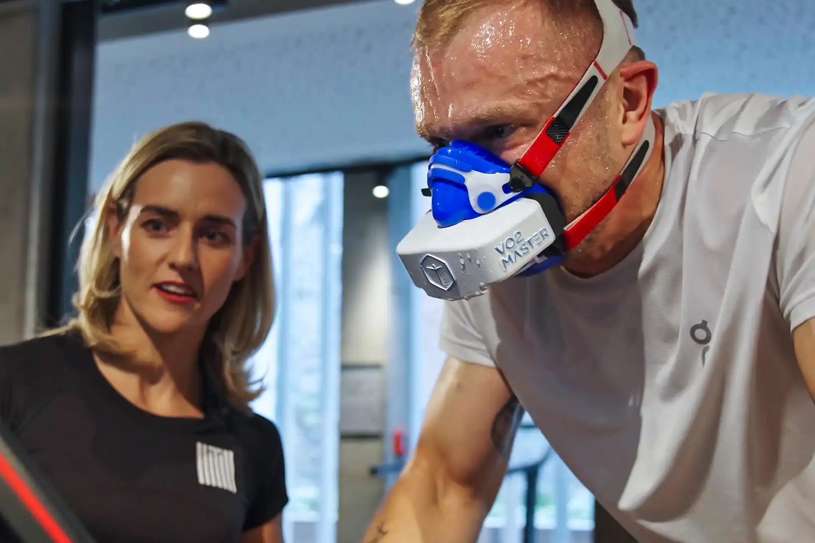 Fitness professional monitoring a client completing VO2 Max testing with a VO2 Master Analyzer during exercise.