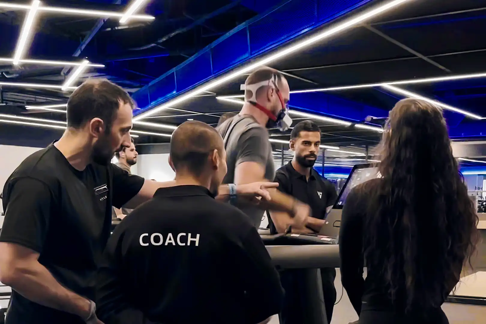 Septovate Coaches supervising VO2 Max testing on a treadmill using a portable metabolic analyzer in a fitness facility.