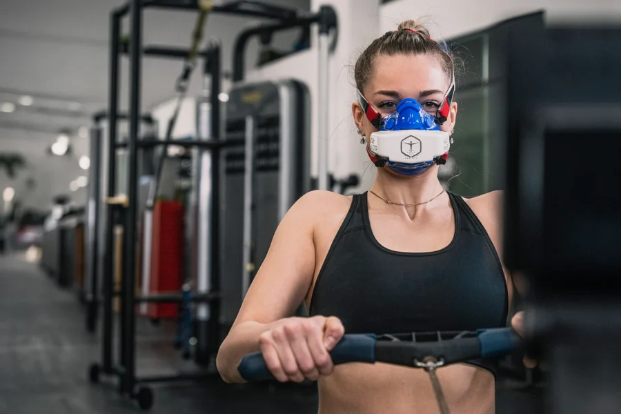 Female athlete wearing a VO2 Master mask during maximal exercise testing in a gym setting for tactical recovery research.